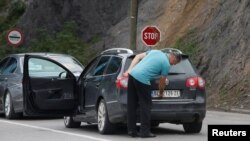 Водитель снимает временную косовскую наклейку с сербского номерного знака в Яринье, на косовско-сербской границе, 1 сентября 2022 года 